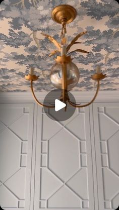 a chandelier hanging from the ceiling in a room with blue and white wallpaper