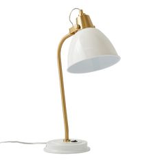 a white and gold desk lamp on a white surface with a cord attached to it