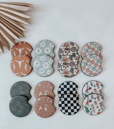 six buttons with different designs on them sitting next to a palm leaf and other items