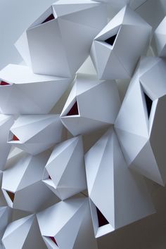 an abstract white sculpture with red accents on the top and bottom part, made out of folded paper