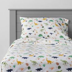 a bed with dinosaurs on it and white sheets