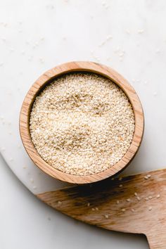 a wooden bowl filled with sesame seeds on top of a cutting board