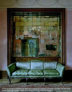 a couch sitting in front of a large mirror