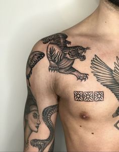 a man with tattoos on his chest and two birds flying over him, one is holding a cross