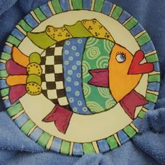 a decorative plate with fish painted on it's side, sitting on a blue towel