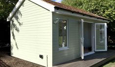 a small white shed sitting on top of a wooden deck