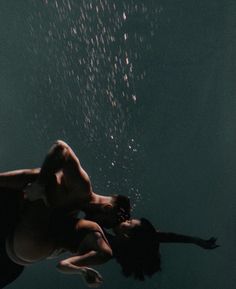 two people swimming under water with bubbles coming off the bottom of their heads and arms