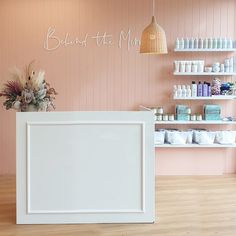 a white counter sitting inside of a store next to shelves filled with bottles and flowers