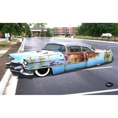 an old blue car parked in the middle of a parking lot with rust on it