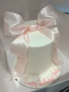 a white cake with pink ribbon and happy birthday written on it