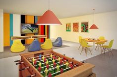 a room filled with lots of furniture and colorful decorations on the walls, including a foosball table