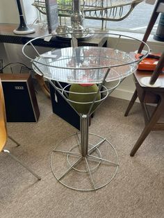 a glass table with two chairs and an apple on it in front of a window