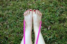 a woman's bare feet with pink nail polish and red fingernails on the grass