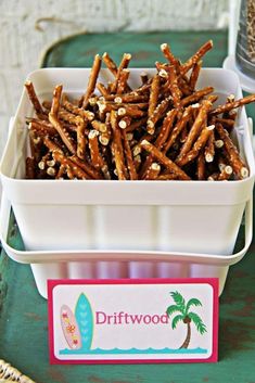 a container filled with pretzels sitting on top of a green table next to a sign