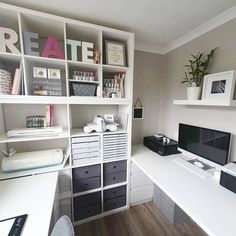 a white desk topped with lots of drawers next to a wall mounted computer monitor and printer