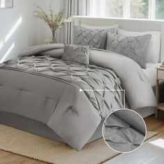 a bed with grey comforter and pillows in a room