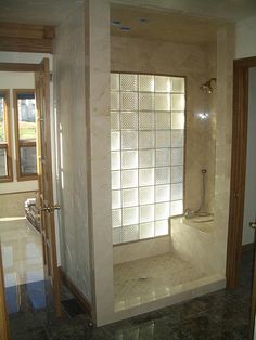 a bathroom with a walk in shower sitting next to a window and tiled flooring