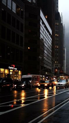 the city street is busy with cars and people walking on it at night in the rain