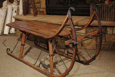 an old fashioned wooden sled sitting in front of a fireplace