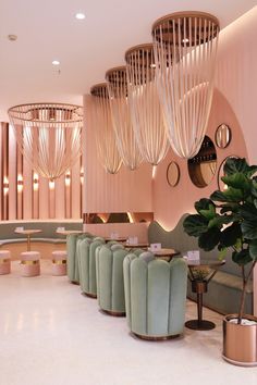 the interior of a modern restaurant with pink walls and gold chandeliers hanging from the ceiling