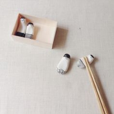 two wooden chopsticks in a box next to some black and white objects on a table