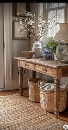 a wooden table with baskets on top of it next to a lamp and vases