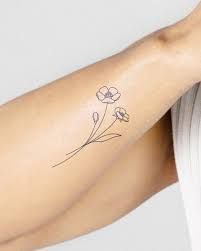 a woman's arm with a small flower tattoo on the left side of her arm