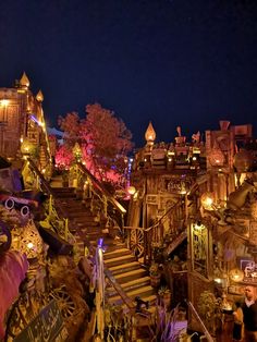 the stairs are lit up at night in front of buildings and trees with lights on them