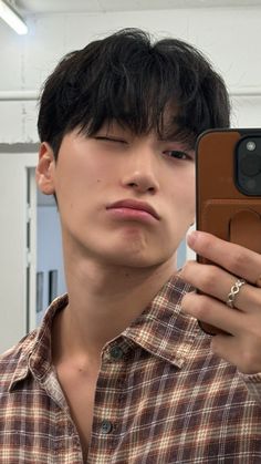 a man taking a selfie with his cell phone in front of him and wearing a plaid shirt