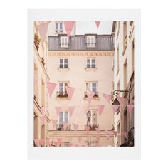 pink and white flags hanging from the side of buildings