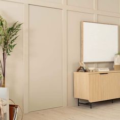 a living room with a plant and a mirror on the wall next to a dresser