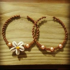 two bracelets with flowers and pearls are sitting on a wooden surface, next to each other