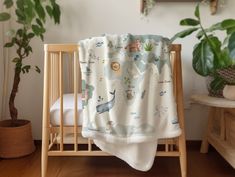 a baby's crib with a blanket on it and a potted plant in the corner