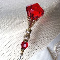 a close up of a red brooch on a white shirt with gold chains and beads