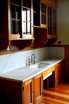 a kitchen with wooden cabinets and white marble counter tops, along with hardwood flooring