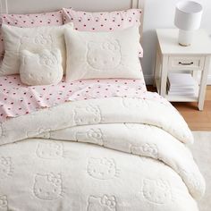 a white bed with hello kitty pillows and pink polka dot bedspread in a bedroom