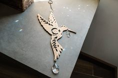 a wooden hummingbird hanging from a chain on a counter top next to a window