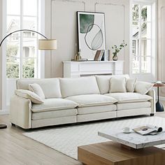 a living room filled with white furniture and lots of window sills on the walls