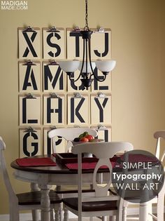 a dining room table and chairs in front of a wall with letters hanging on it