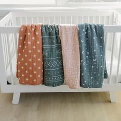 three blankets hanging on the side of a crib