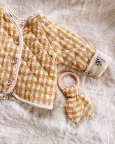 a yellow and white checkered jacket next to a wooden rattler on a bed