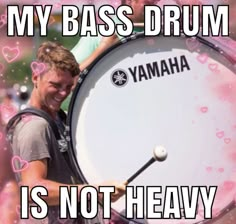 a man holding a large drum with words on it that say, my bass drum is not heavy