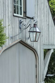 an old wooden building with a light on the side and a lamp hanging from it's side