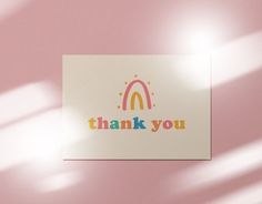 a thank you card on a pink background with the word thank you written in rainbow colors