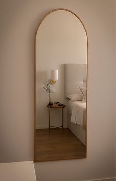 an arched mirror in the corner of a room with a small table and lamp next to it