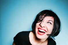 a woman with black hair and piercings on her head is smiling at the camera