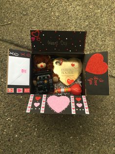 a teddy bear in a valentine's day box on the ground next to an envelope