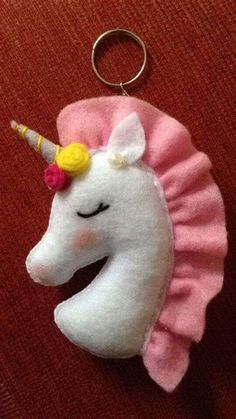 a stuffed unicorn keychain with a pink skirt and yellow horn on it's head