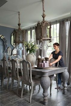 a person sitting at a table with vases on it and an open window in the background