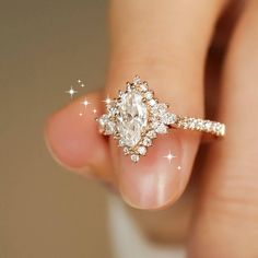 a woman's hand holding an engagement ring with diamonds on the band and side